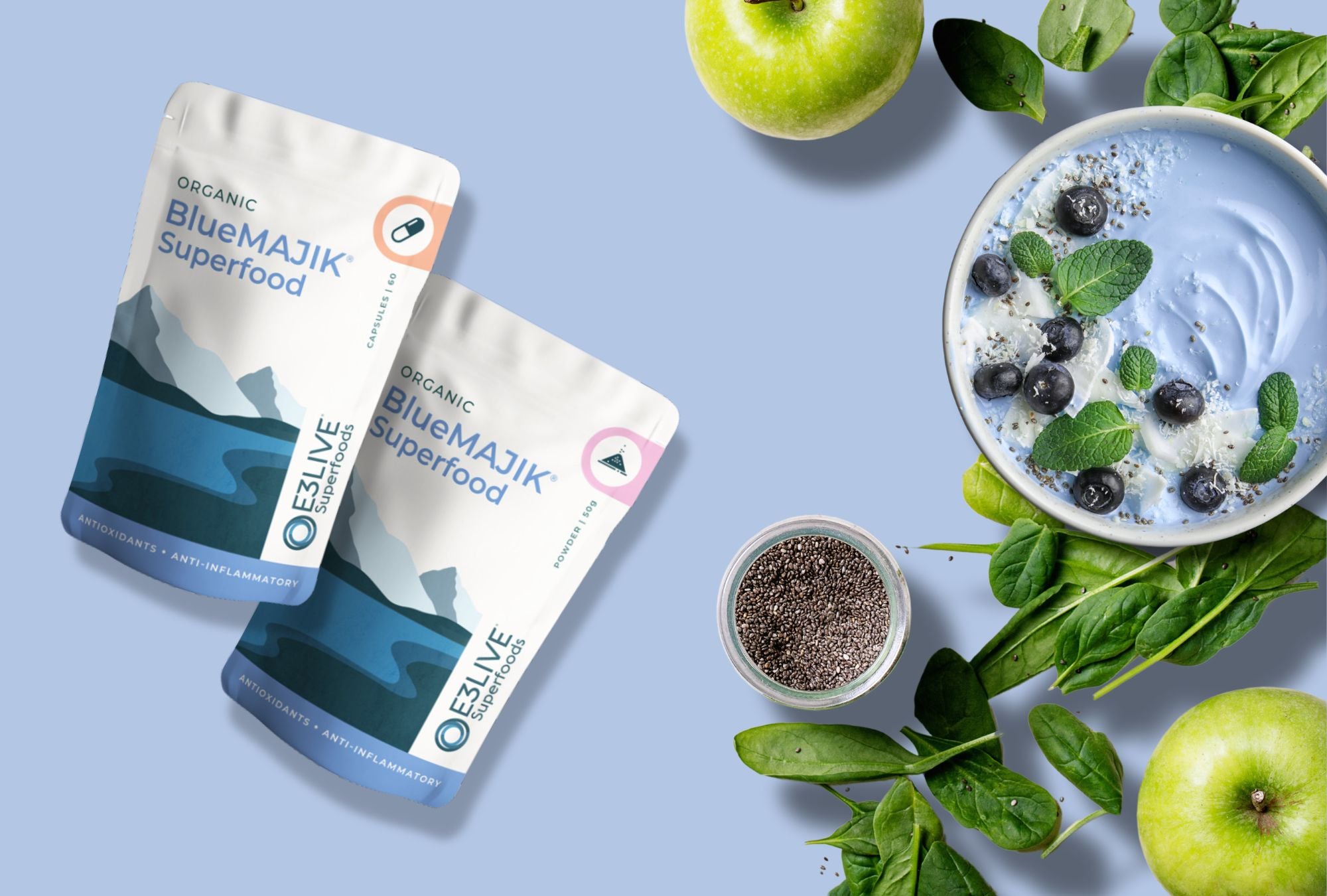 Organic BlueMAJIK Superfood capsules and powder packaging alongside fresh spinach, chia seeds, green apple, and a blue smoothie bowl, representing BlueMAJIK products with antioxidants and anti-inflammatory properties.