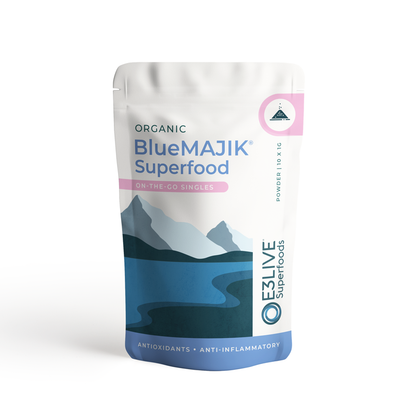 A close-up view of a packet containing 10 x 1g BlueMAJIK® On-The-Go Singles dietary supplement powder. The label on the packet shows the product name, and the powder is a vibrant blue in color.