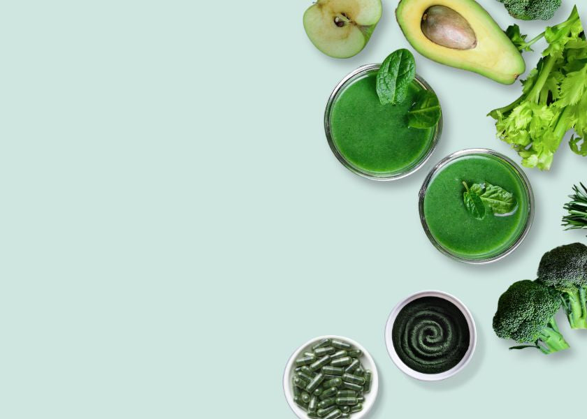 A selection of green ingredients including avocado, pear, broccoli, and leafy greens, arranged alongside glasses of green smoothies and small dishes containing BrainON powder and capsules, and highlights BrainON products, known for supporting cognitive health, mental clarity, and focus through nutrient-rich, plant-based ingredients.