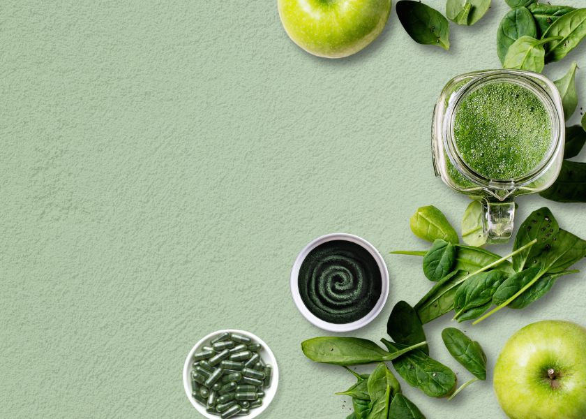 Green apples, fresh spinach leaves, a jar of green juice, displayed with bowls of E3AFA powder and capsules.