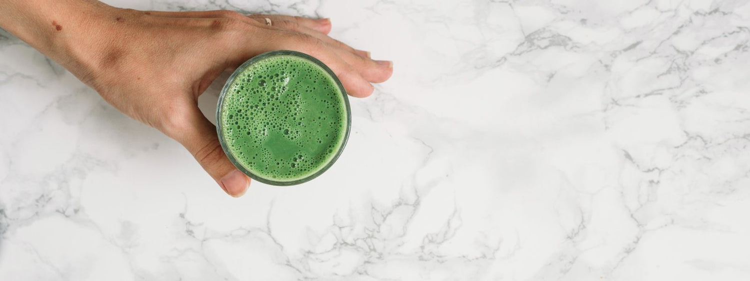 Close-up of a woman holding a healthy green smoothie, representing E3Live's signature superfood for vitality, energy, and overall wellness.